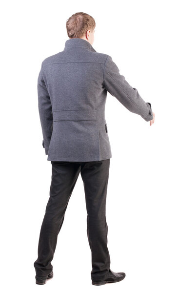 back view of businessman in coat reaches out to shake hands.