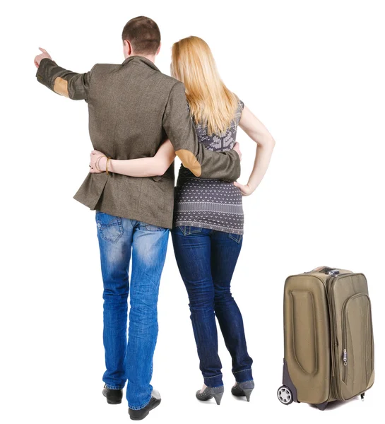 Back view of traveling young couple with suitcas pointing — Stock Photo, Image