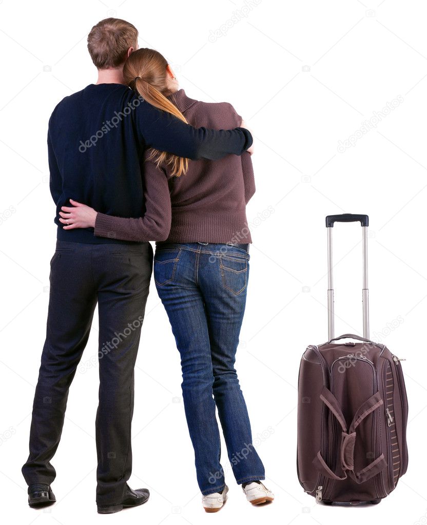 Back view of traveling young couple with suitcas
