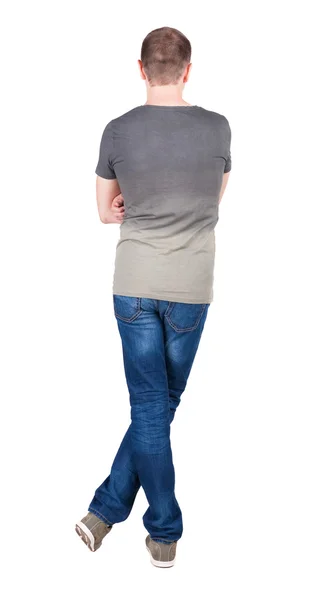 Back view of young man in t-shirt and jeans looking. — Stock Photo, Image