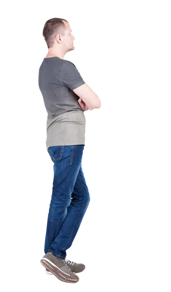 Bakifrån av ung man i t-shirt och jeans ser. — Stockfoto