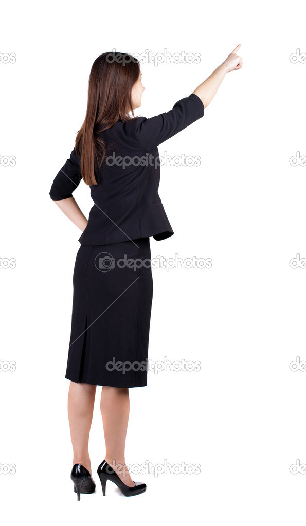 Back view of young brunette business woman pointing at wall.