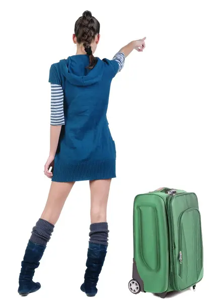 दीवार पर इंगित सूटकेस के साथ पोशाक में यात्रा करने वाली युवा महिला — स्टॉक फ़ोटो, इमेज