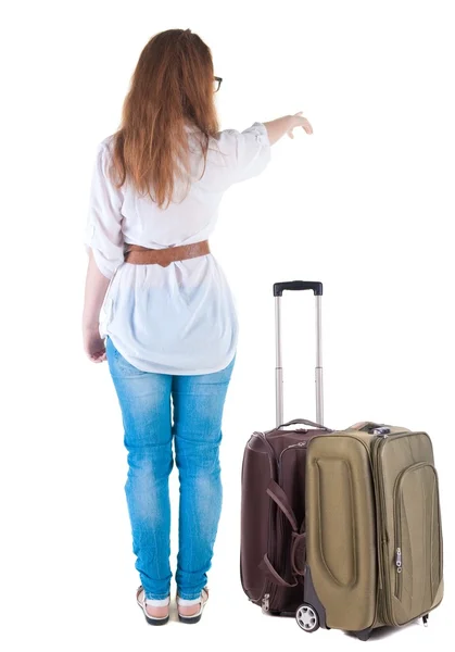 Giovane donna con suitcas punti a muro in viaggio. — Foto Stock