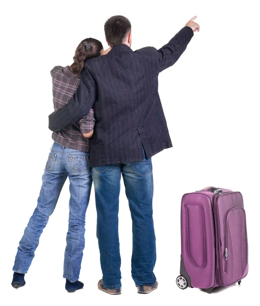 Traveling young couple with suitcas pointing at wall. Back view — Stock Photo, Image