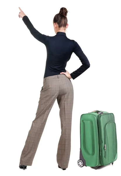 Traveling young woman with suitcas pointing at wall. — Stock Photo, Image