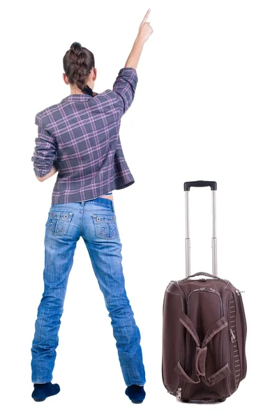 Traveling young woman with suitcas pointing at wall. — Stock Photo, Image