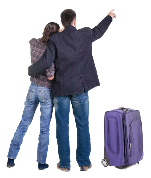 Traveling young couple with suitcas pointing at wall. Back view — Stock Photo, Image