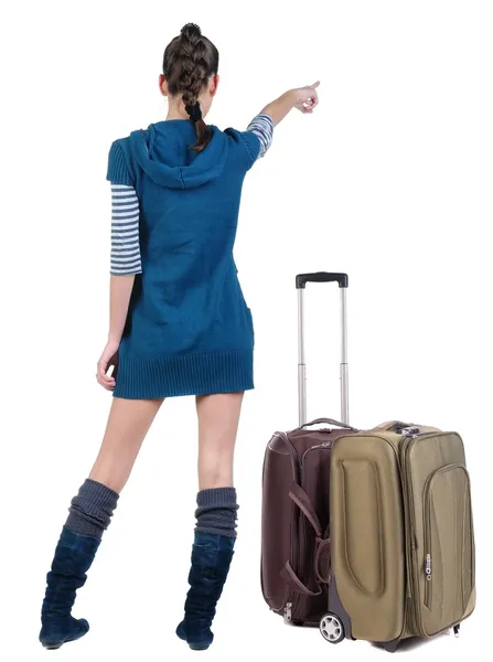 Reizen van jonge vrouw in jurk met koffer wijzend op de muur — Stockfoto