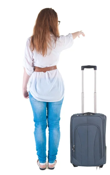 Giovane donna con suitcas punti a muro in viaggio. — Foto Stock