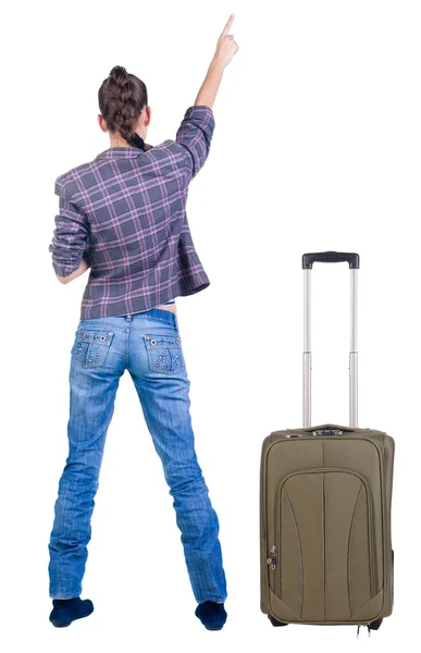 Traveling young woman with suitcase pointing at wall. — Stock Photo, Image