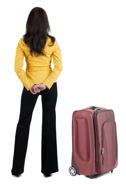 Traveling young woman with suitcase in yellow suit looking at wall — Stock Photo, Image