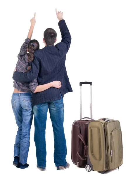 Pareja joven acompaña maleta apuntando a la pared. Vista posterior — Foto de Stock