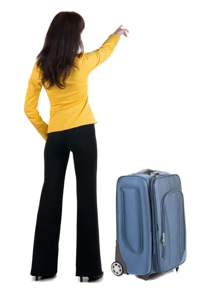 Young traveling woman with suitcas points at wall. — Stock Photo, Image
