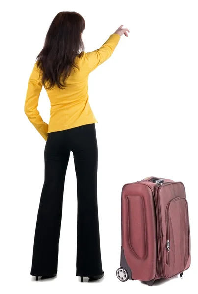 Ung resande kvinna med suitcas pekar på väggen. — Stockfoto