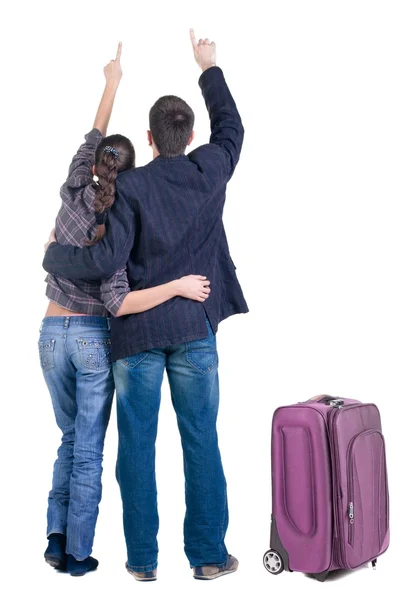 Traveling young couple with suitcas pointing at wall. Back view — Stock Photo, Image