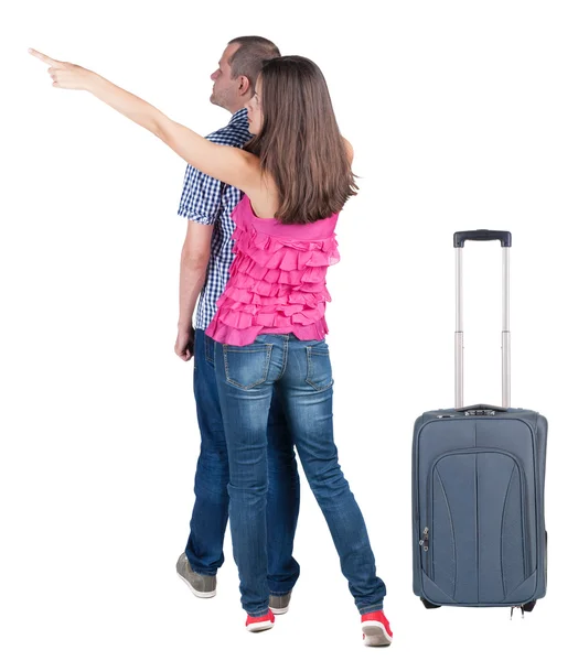 Young couple traveling with suitcas and pointing at wall — Stock Photo, Image