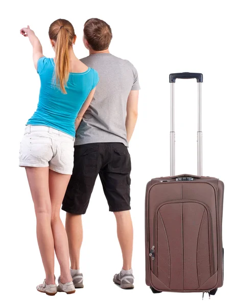 Ungt par reser med resväska och pekar på väggen — Stockfoto