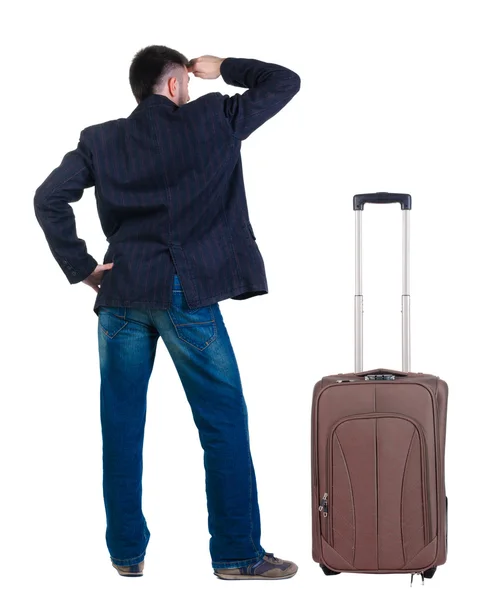 Young man traveling with suitcase looks ahead. Rear view. — Stock Photo, Image