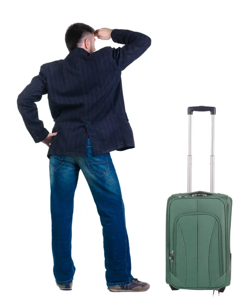 Young man traveling with suitcase looks ahead. Rear view. — Stock Photo, Image