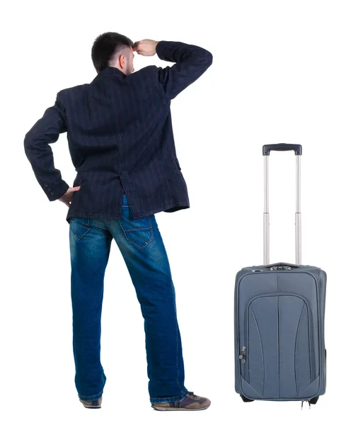 Young man traveling with suitcase looks ahead. Rear view. — Stock Photo, Image