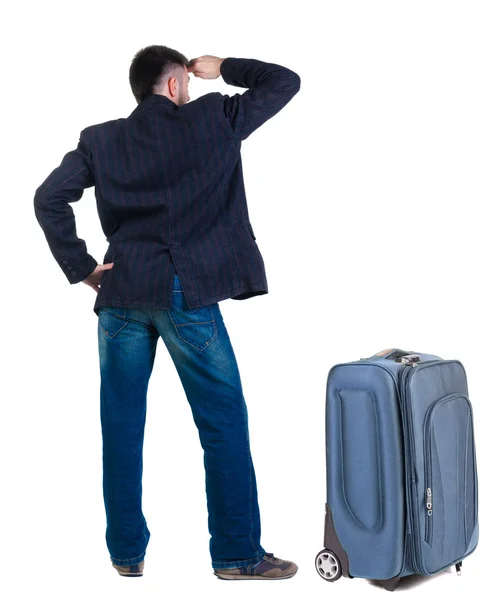 Young man traveling with suitcase looks ahead. Rear view. — Stock Photo, Image