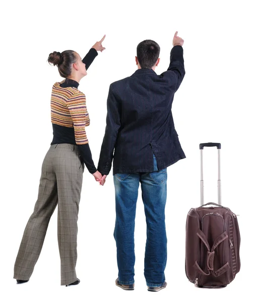 Young couple traveling with suitcase and pointing at wall — Stock Photo, Image