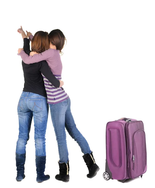 Dos mujeres viajan con maleta y apuntando a la pared. —  Fotos de Stock