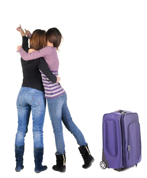 Dos mujeres viajan con maleta y apuntando a la pared. —  Fotos de Stock