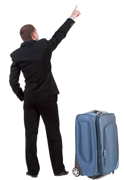 Powrót widok wskazując człowiek biznesu podróżujących z walizką. — Zdjęcie stockowe