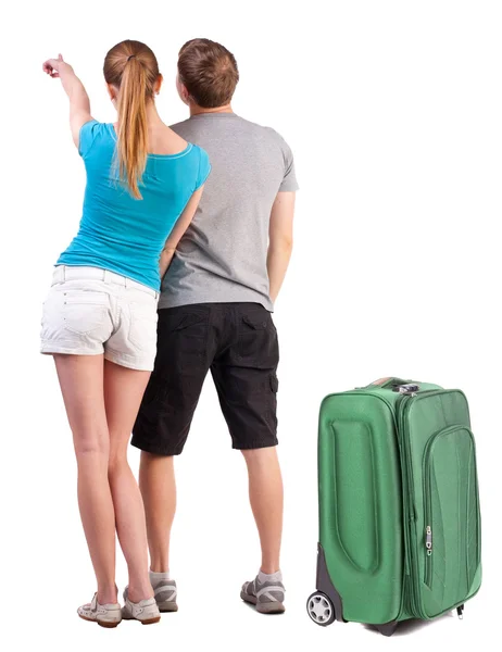 Young couple traveling with suitcas and pointing at wall — Stock Photo, Image