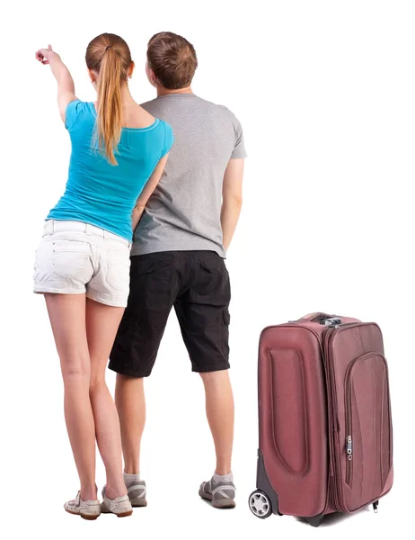 Jovem casal viajando com suitcas e apontando para a parede — Fotografia de Stock