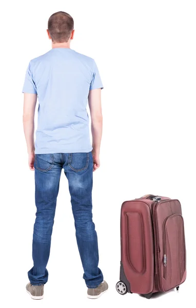 Back view of young man traveling with suitcase. – stockfoto