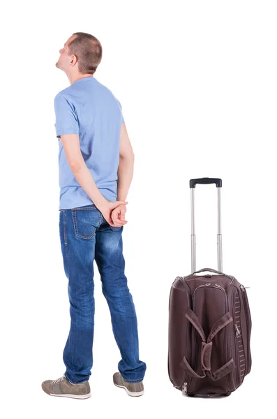 Achteraanzicht van de jonge man het reizen met koffer. — Stockfoto