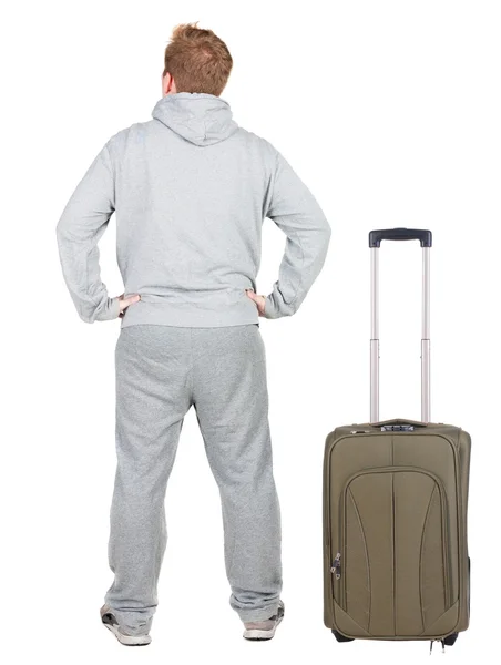 Back view of young man traveling with suitcase. - Stock-foto