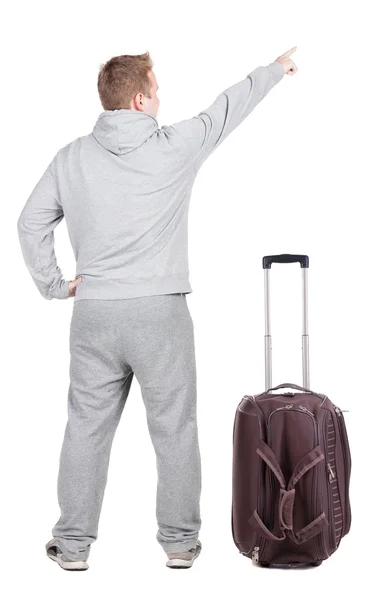 Back view of pointing young men traveling with suitcase. — Stock Photo, Image