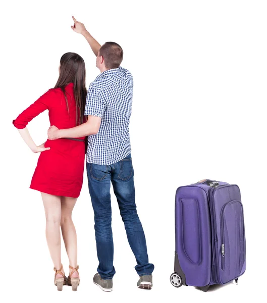 Jovem casal viajar com mala e apontando para a parede — Fotografia de Stock