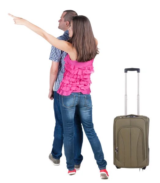 Młoda para podróż z suitcas i wskazując na ścianie — Zdjęcie stockowe