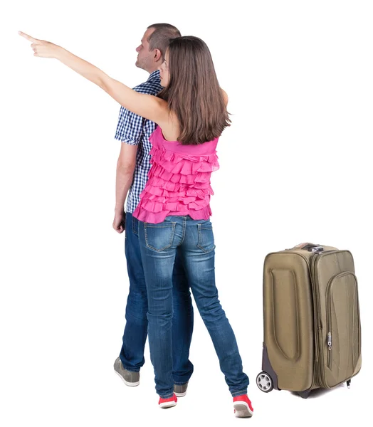 Young couple traveling with suitcas and pointing at wall — Stock Photo, Image