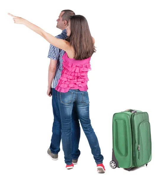 Pareja joven viajando con suitcas y apuntando a la pared —  Fotos de Stock