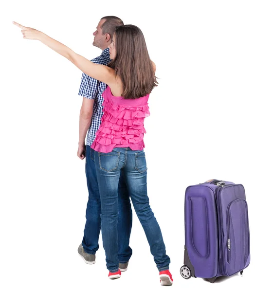 Young couple traveling with suitcas and pointing at wall — Stock Photo, Image