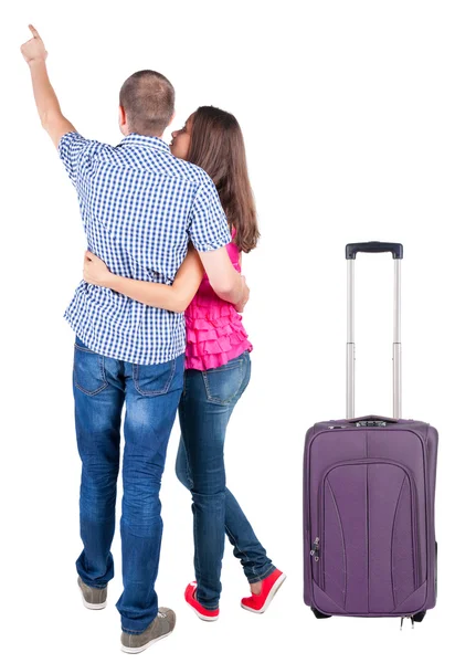 Jeune couple voyageant avec suitcas et pointant à mur — Photo