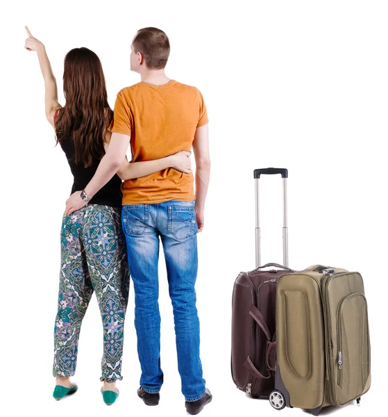 Young couple traveling with suitcas and pointing at wall — Stock Photo, Image