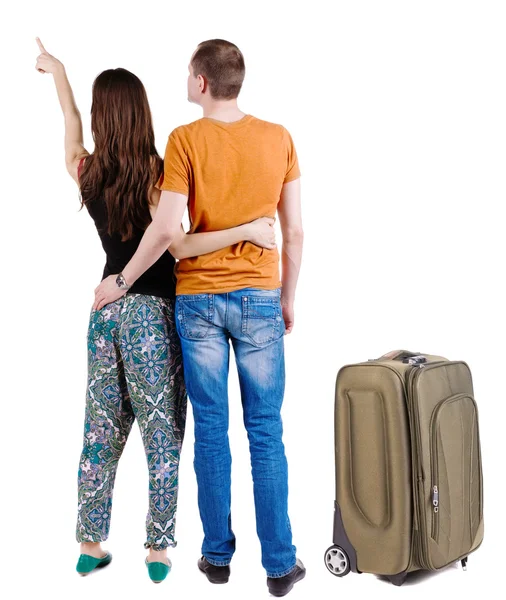 Young couple traveling with suitcas and pointing at wall – stockfoto