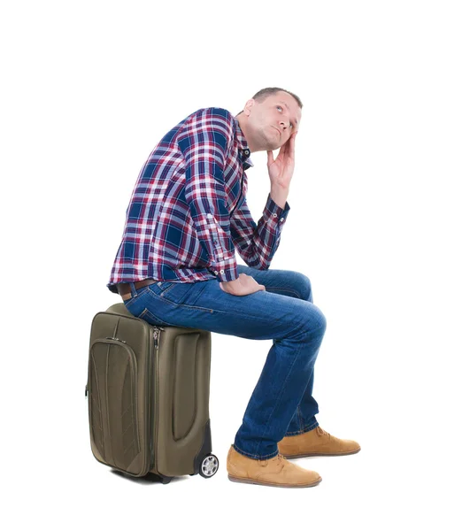 Back view of a man sitting on a suitcase. — Stock Photo, Image