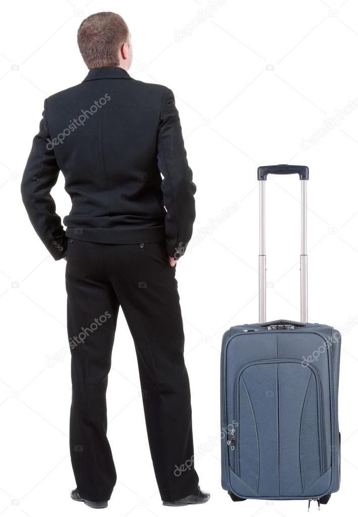 Back view of business man in black suit traveling with suitcase .