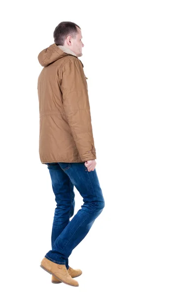 Bakifrån gå stilig man i jeans och jacka. — Stockfoto