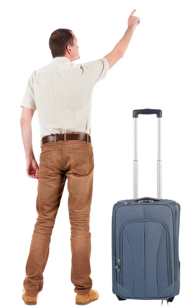 Back view of pointing young man traveling with suitcase. — Stock Photo, Image