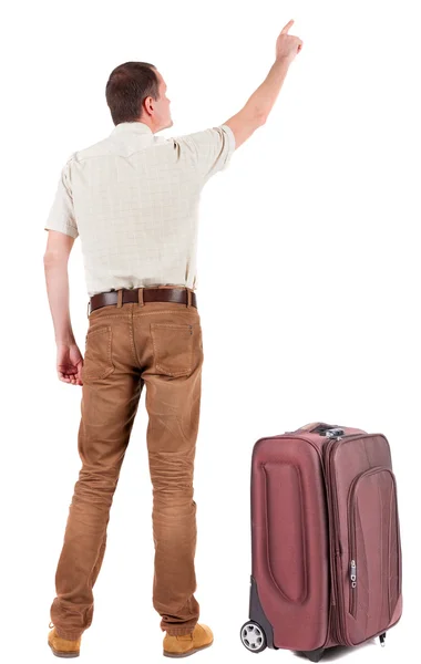 Vue arrière du pointage jeune homme voyageant avec valise. — Photo
