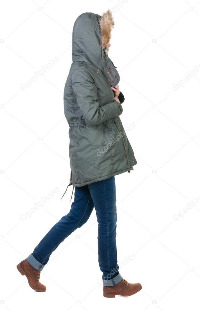 back view of walking woman in winter jacket with hood.